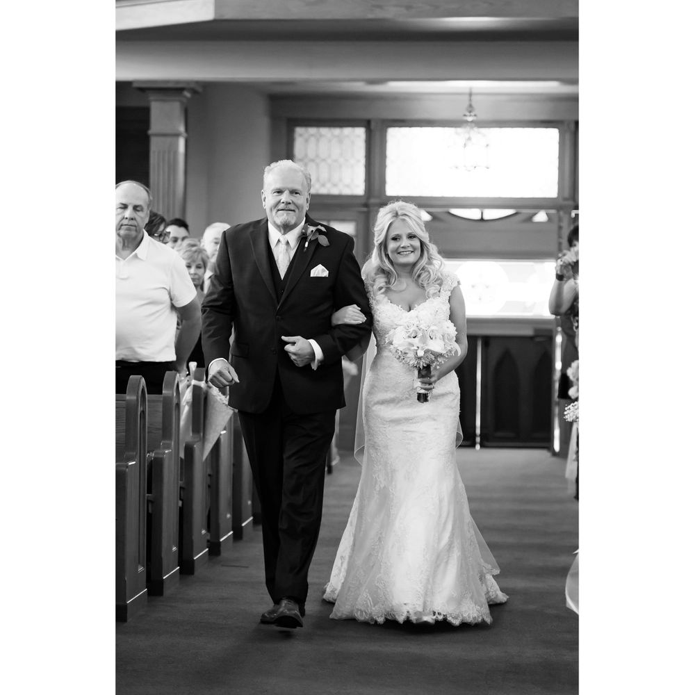 Father walks daughter down aisle during wedding ceremony at Saint Mary Parish in Elyria, Ohio.
