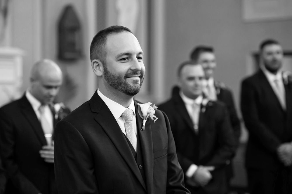 Grooms smiling at bride during wedding processional at Saint Mary Parish in Elyria, Ohio.