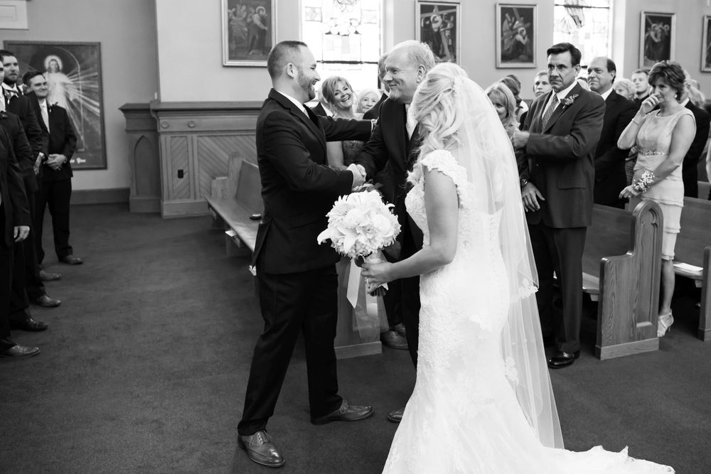 Father hands off daughter to groom during wedding ceremony at Saint Mary Parish in Elyria, Ohio.