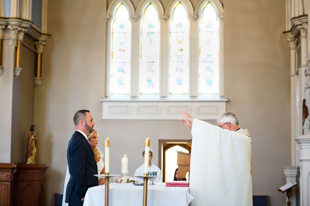 Bride and groom receive blessing during wedding ceremony at Saint Mary Parish in Elyria, Ohio.