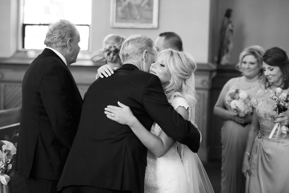 Bride hugs father during wedding ceremony at Saint Mary Parish in Elyria, Ohio.