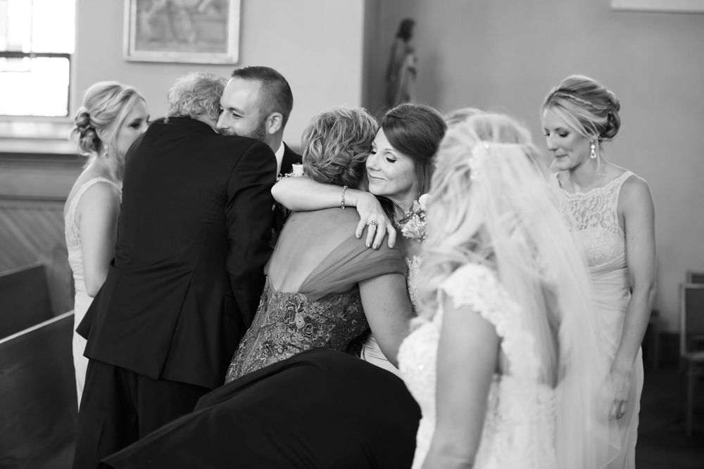 Bride and groom hug parents during wedding ceremony at Saint Mary Parish in Elyria, Ohio.