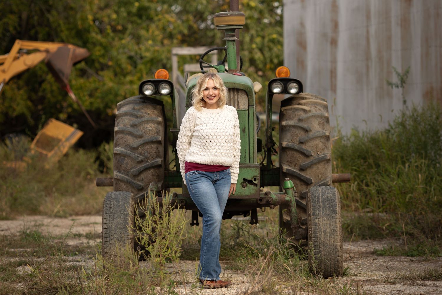 A senior in Mattoon High School stands nicely in front of green John Deere Tractor on her family farm outside of Mattoon, Illinois.