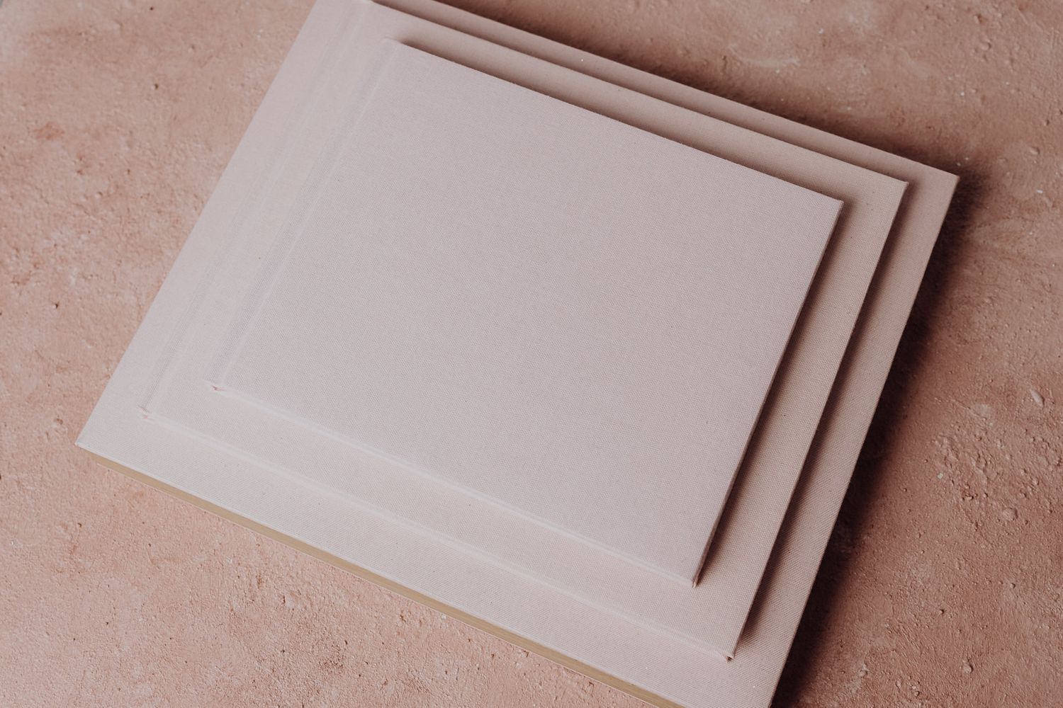 Three layered white photo frames stacked on pink textured surface.