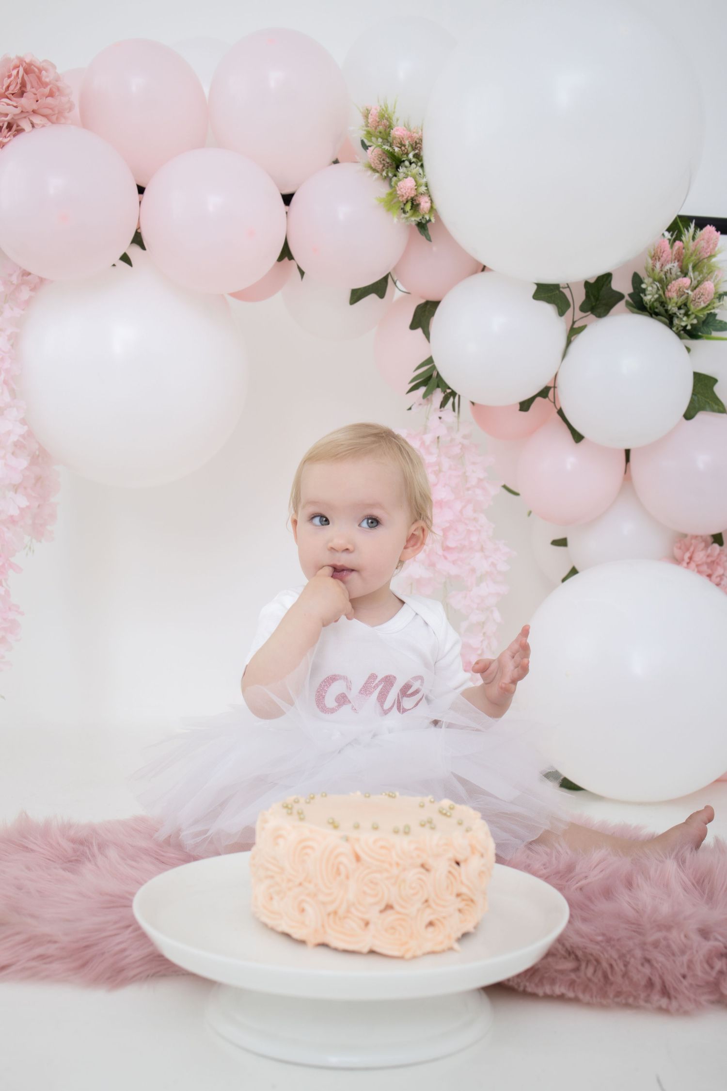 One-year-old cake smash session in Centurion with pastel balloon backdrop and soft, timeless styling