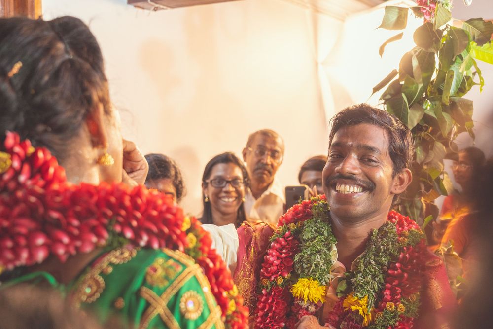 Happy moments during traditional South Indian wedding with flower garlands and festive atmosphere.