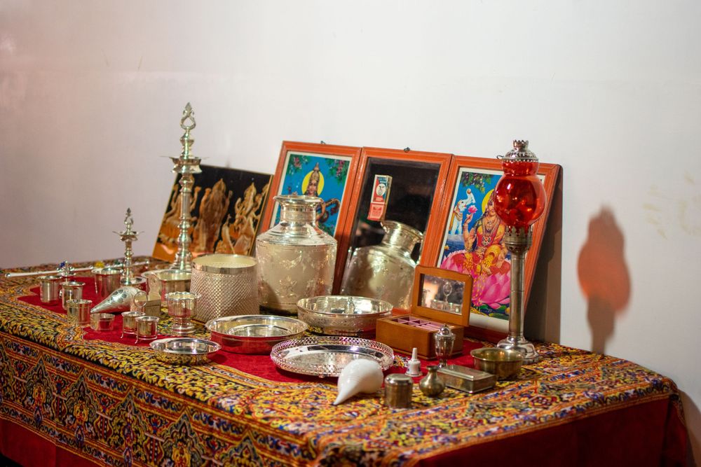 Traditional altar setup with religious icons, candles and decorative items on patterned cloth.