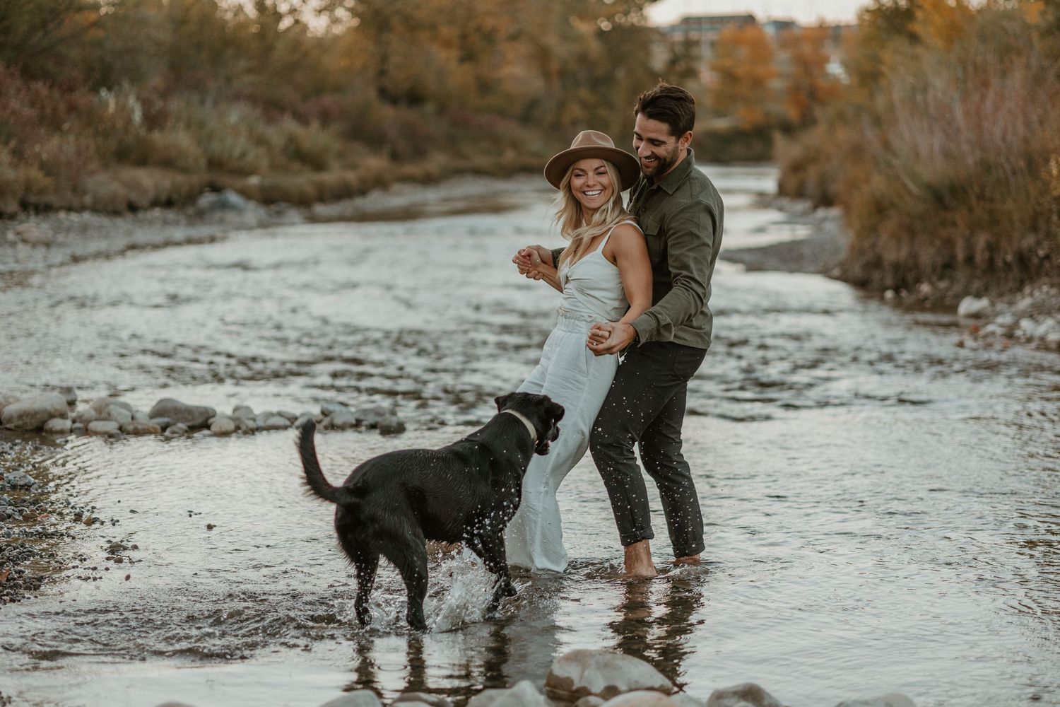 Couple and their dog enjoying a playful moment together in a shallow stream.