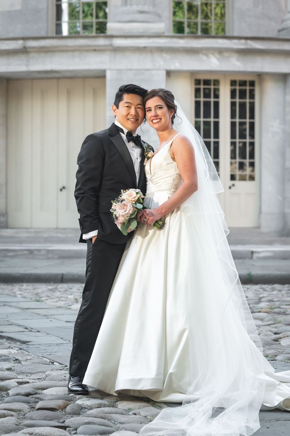 Wedding portrait featuring formal attire against classic architecture and columns.