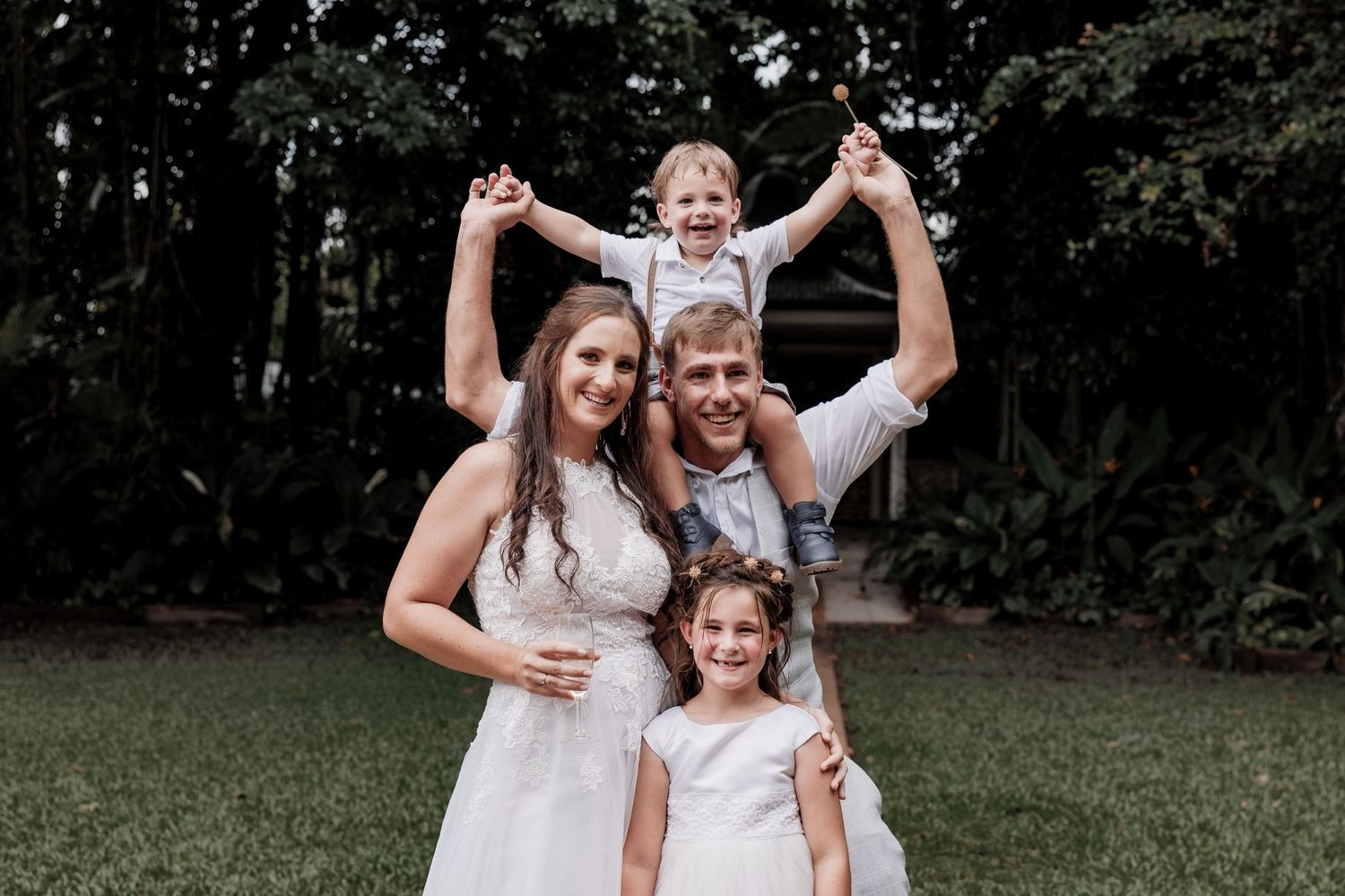 A joyful family moment captured outdoors with playful poses on a grassy lawn.