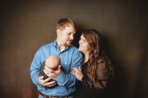 An intimate family moment captured in studio lighting with a newborn baby.