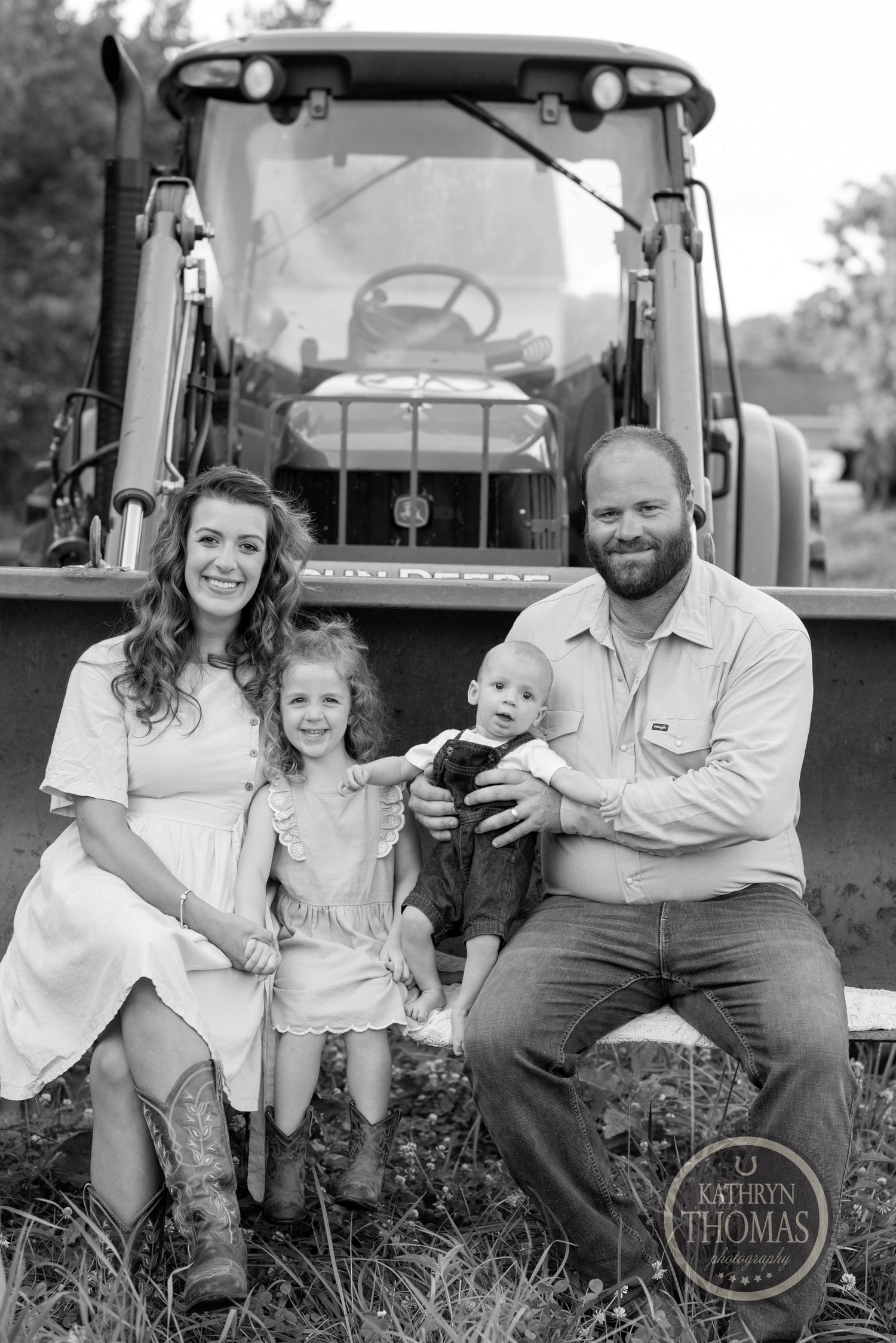 Family sitting together in front of their black tractor for a farm portrait.