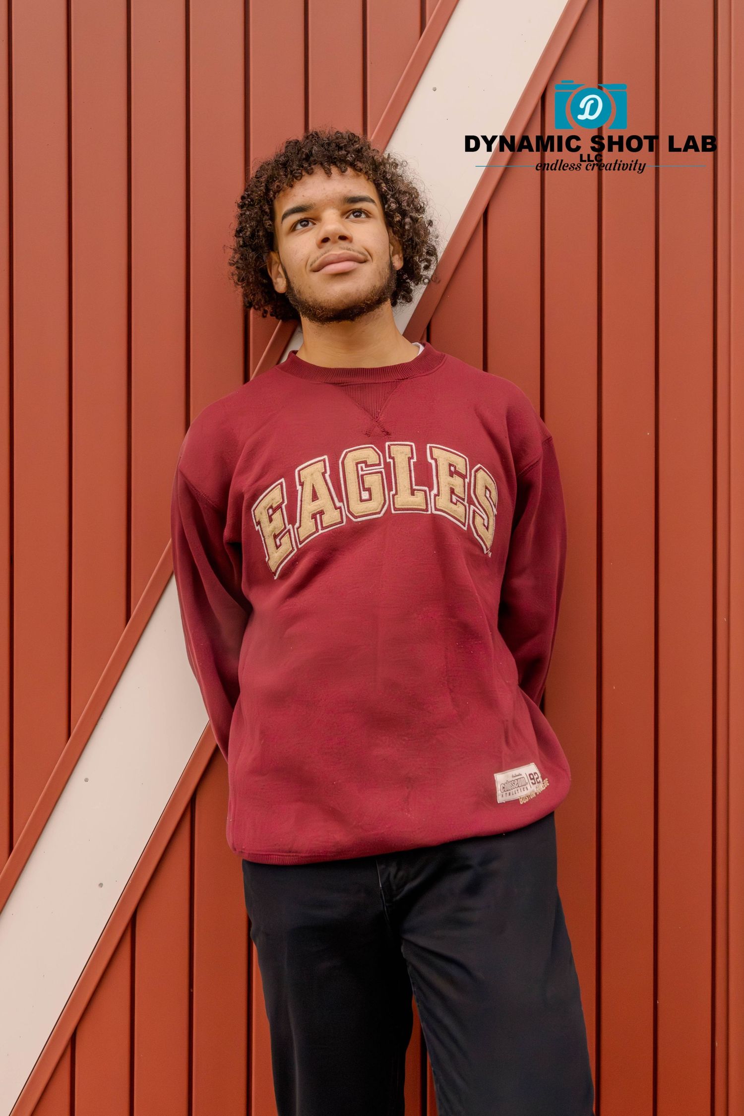 Person in maroon Eagles sweatshirt poses against red and white striped wall.