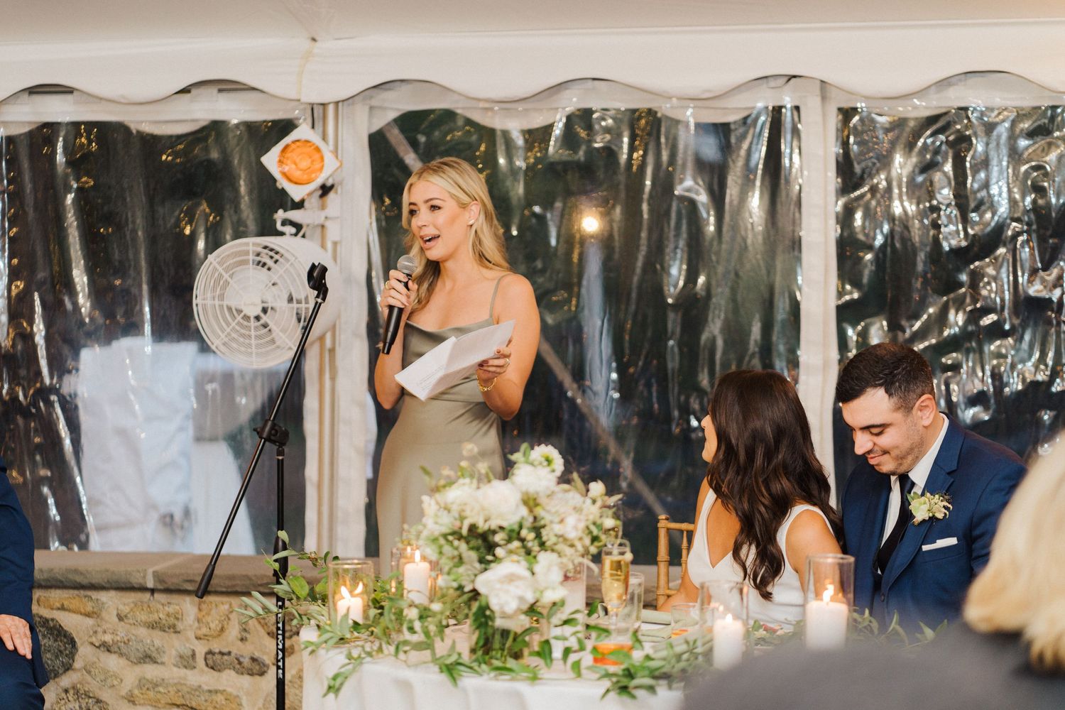 A bridesmaid in a champagne dress gives an emotional speech during the wedding reception.