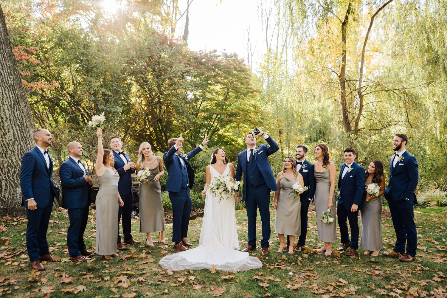 Wedding party raises glasses in celebration during autumn outdoor photo session.