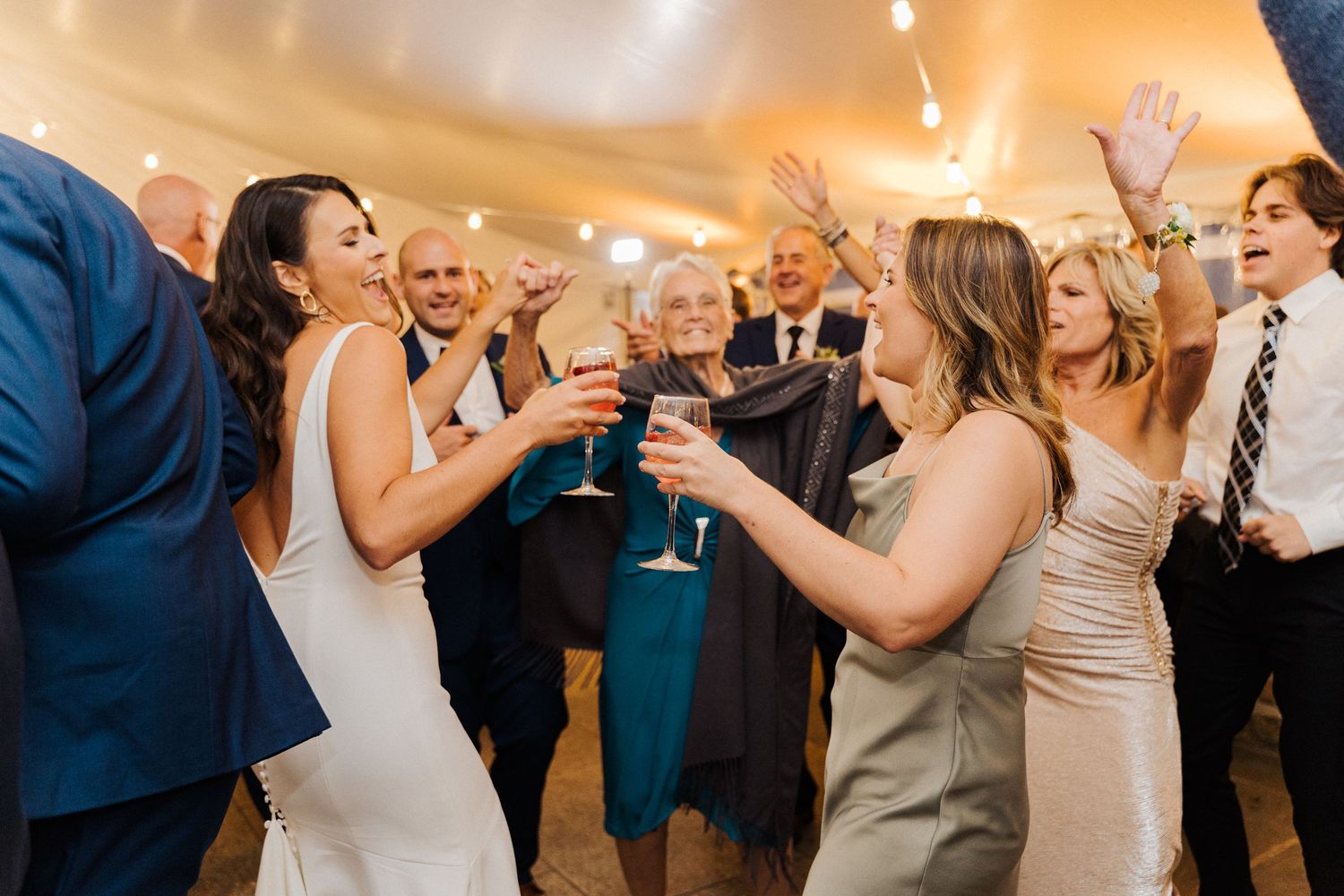 Wedding guests celebrate with champagne toasts during an evening reception.