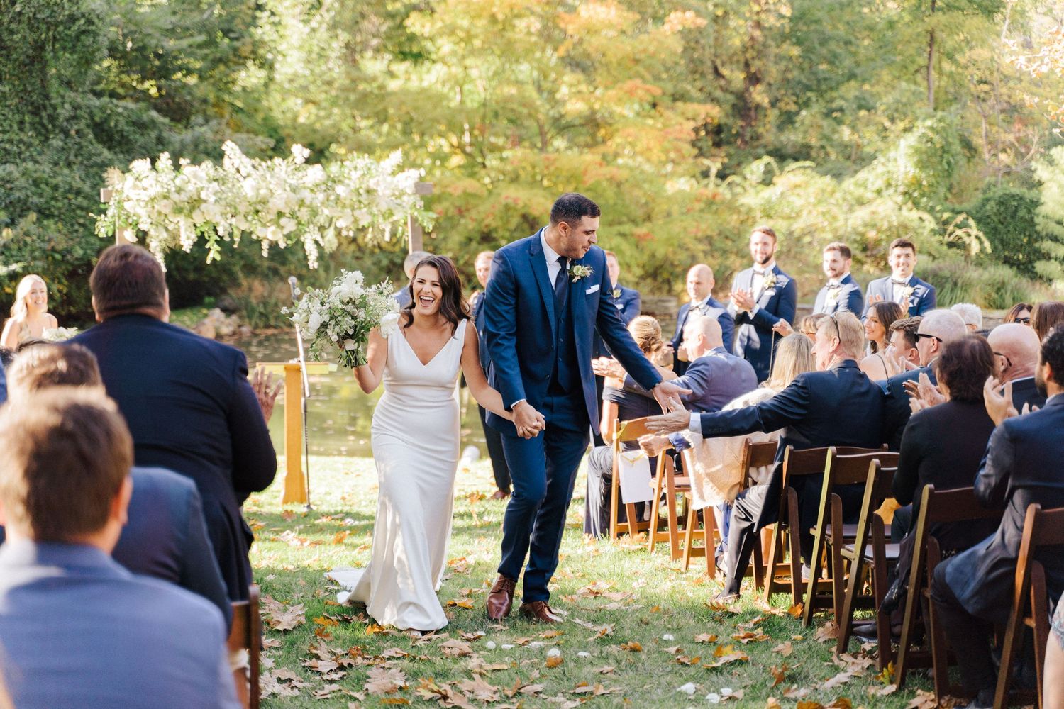A joyful moment during an outdoor garden wedding ceremony with seated guests.
