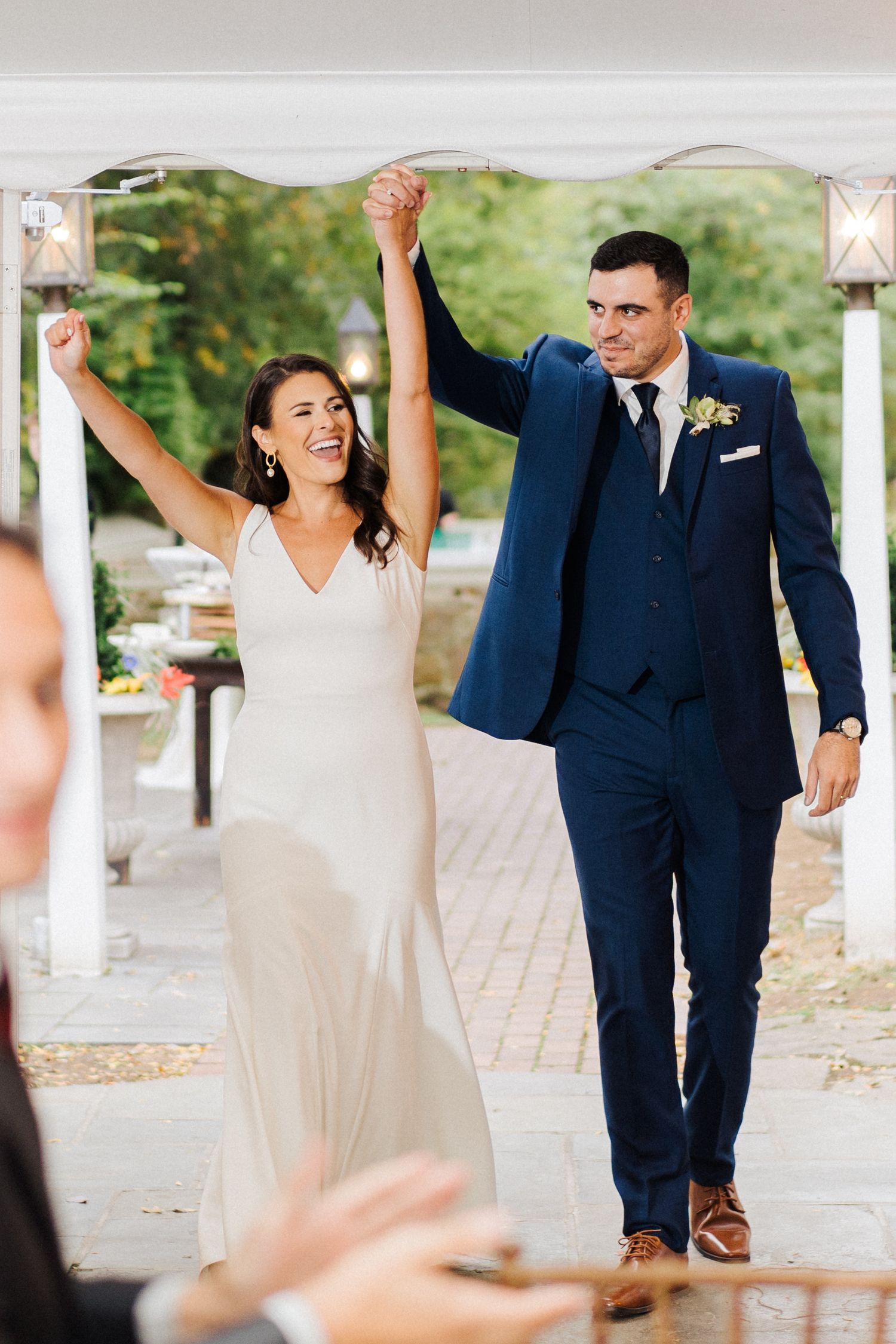 Wedding couple celebrates with raised arms under decorated tent.