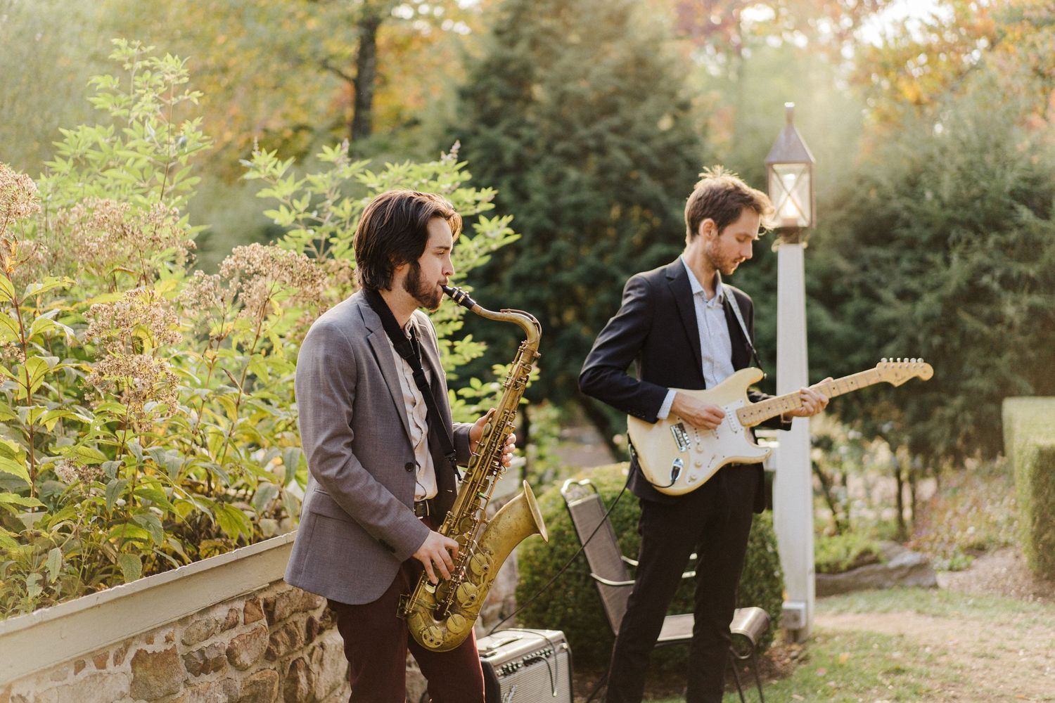 Musicians perform with a saxophone and guitar outdoors during an event.