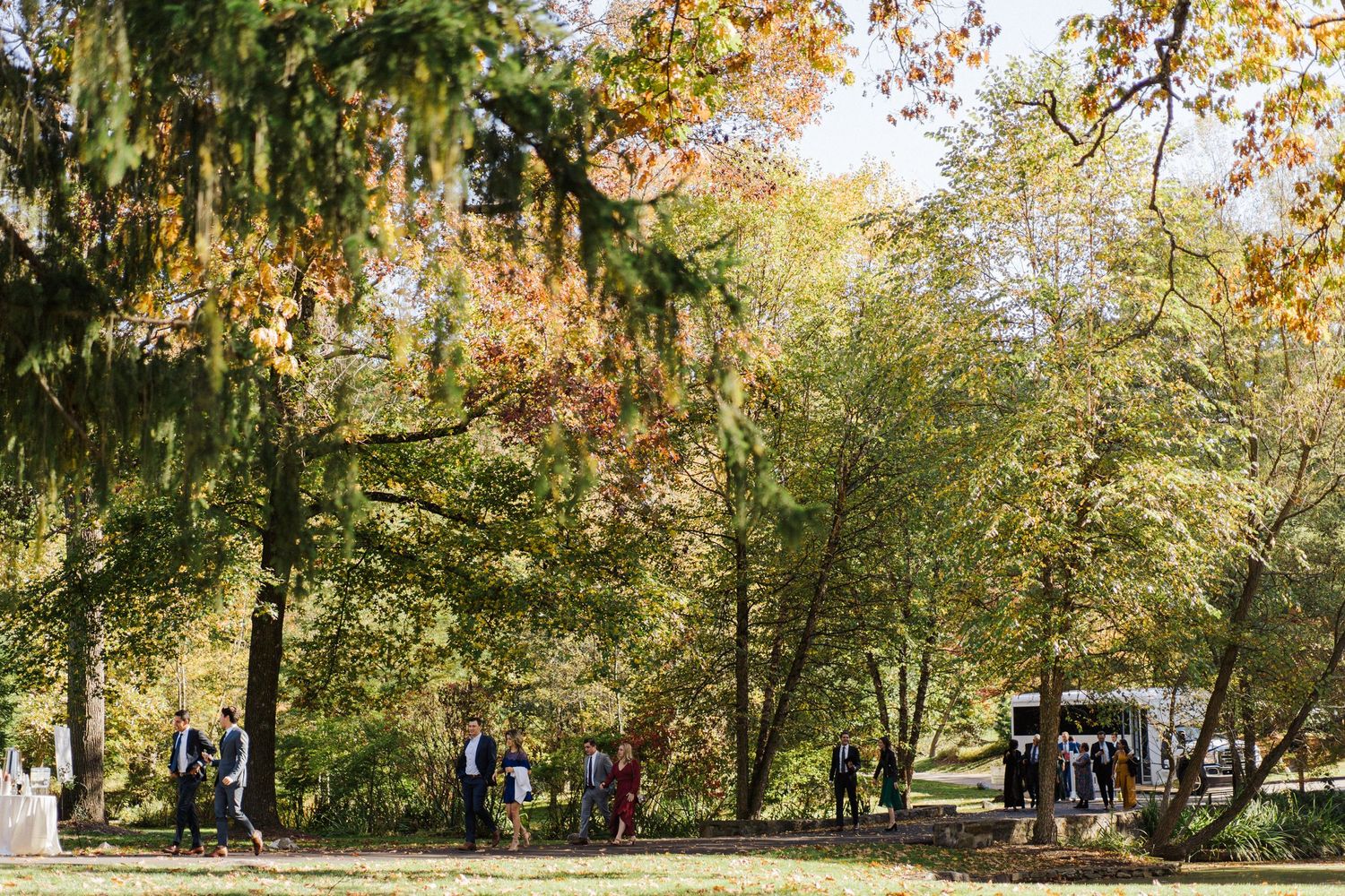 Outdoor wedding venue with guests scattered across a fall landscape.