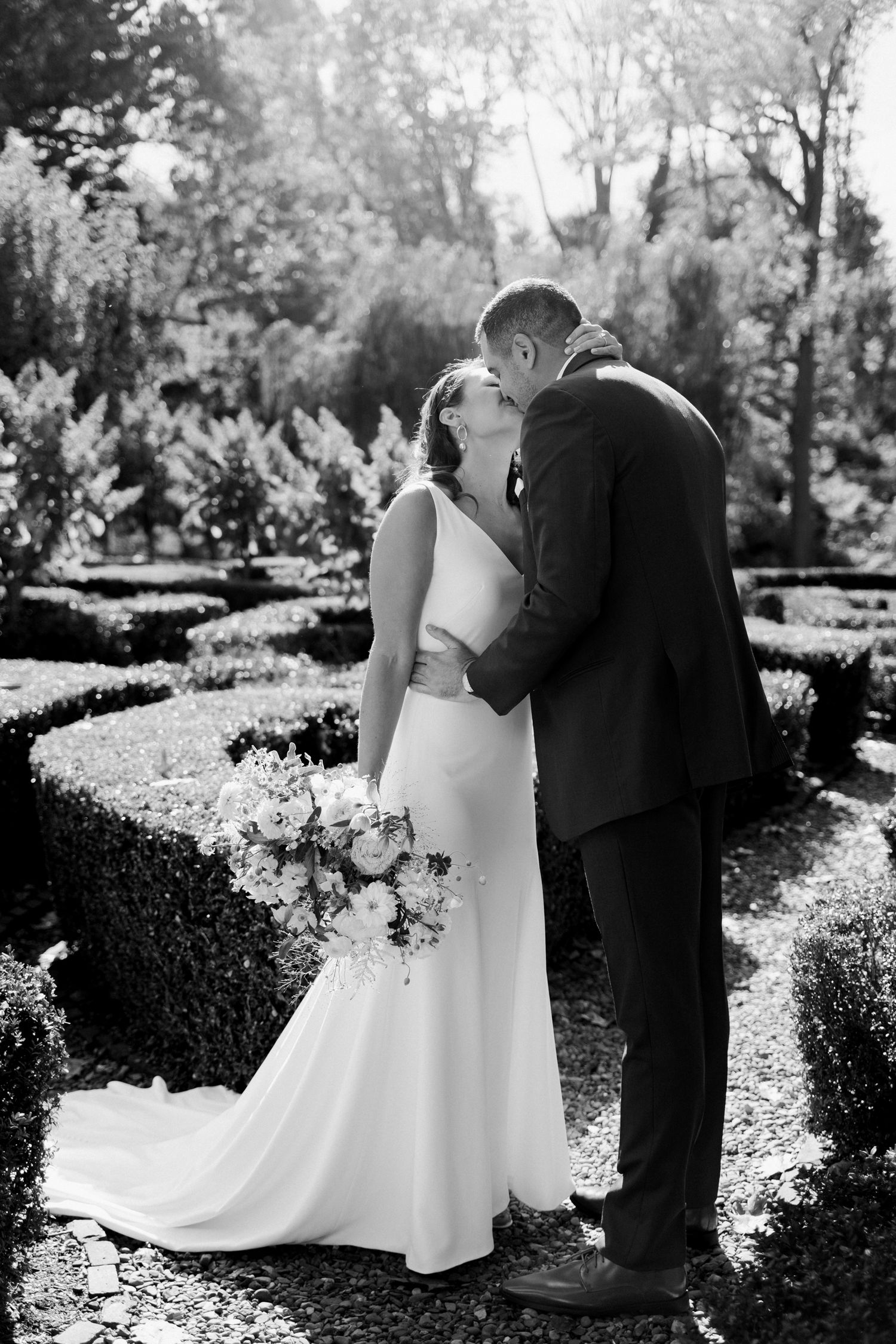 Black and white romantic wedding portrait in garden with hedges.