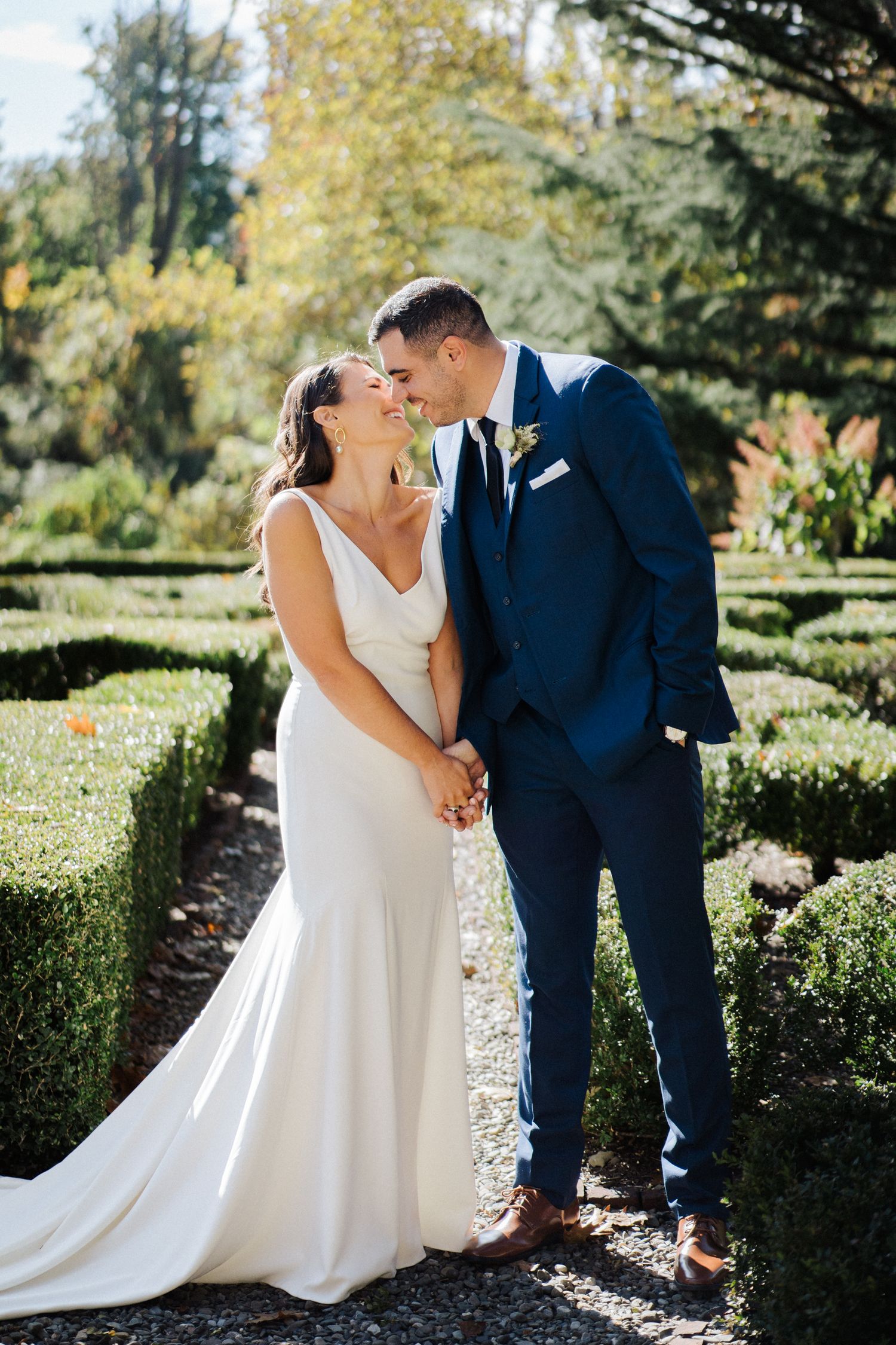 An intimate wedding portrait showing a tender moment in a beautifully landscaped garden setting.