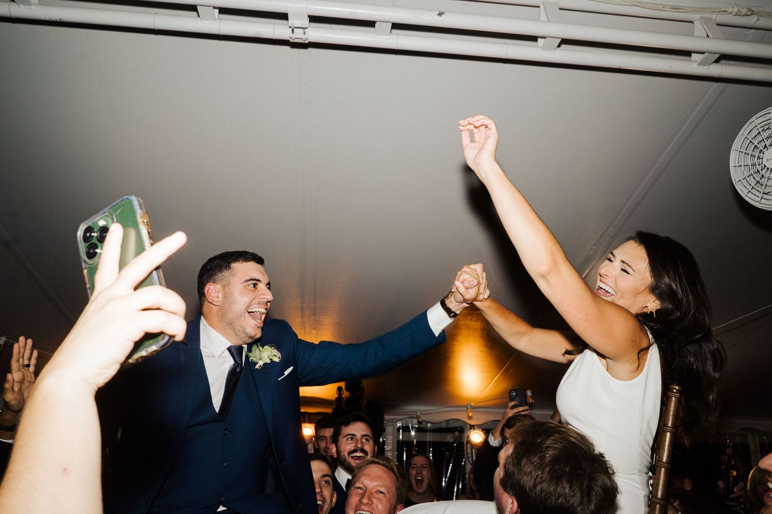 Energetic wedding reception dance floor scene with guests celebrating in a dimly lit venue.