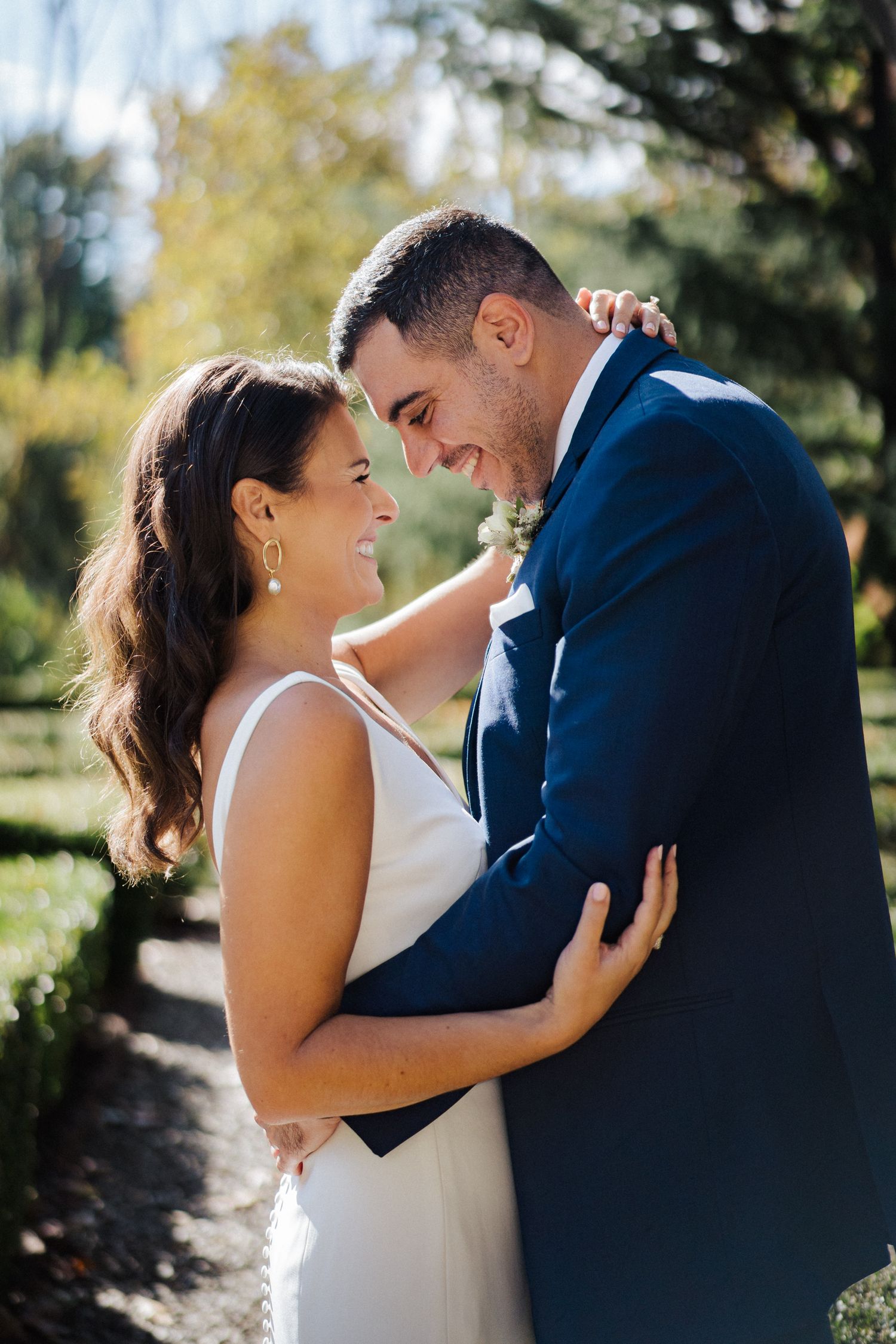 Newlyweds share a joyful candid moment together in a garden setting.