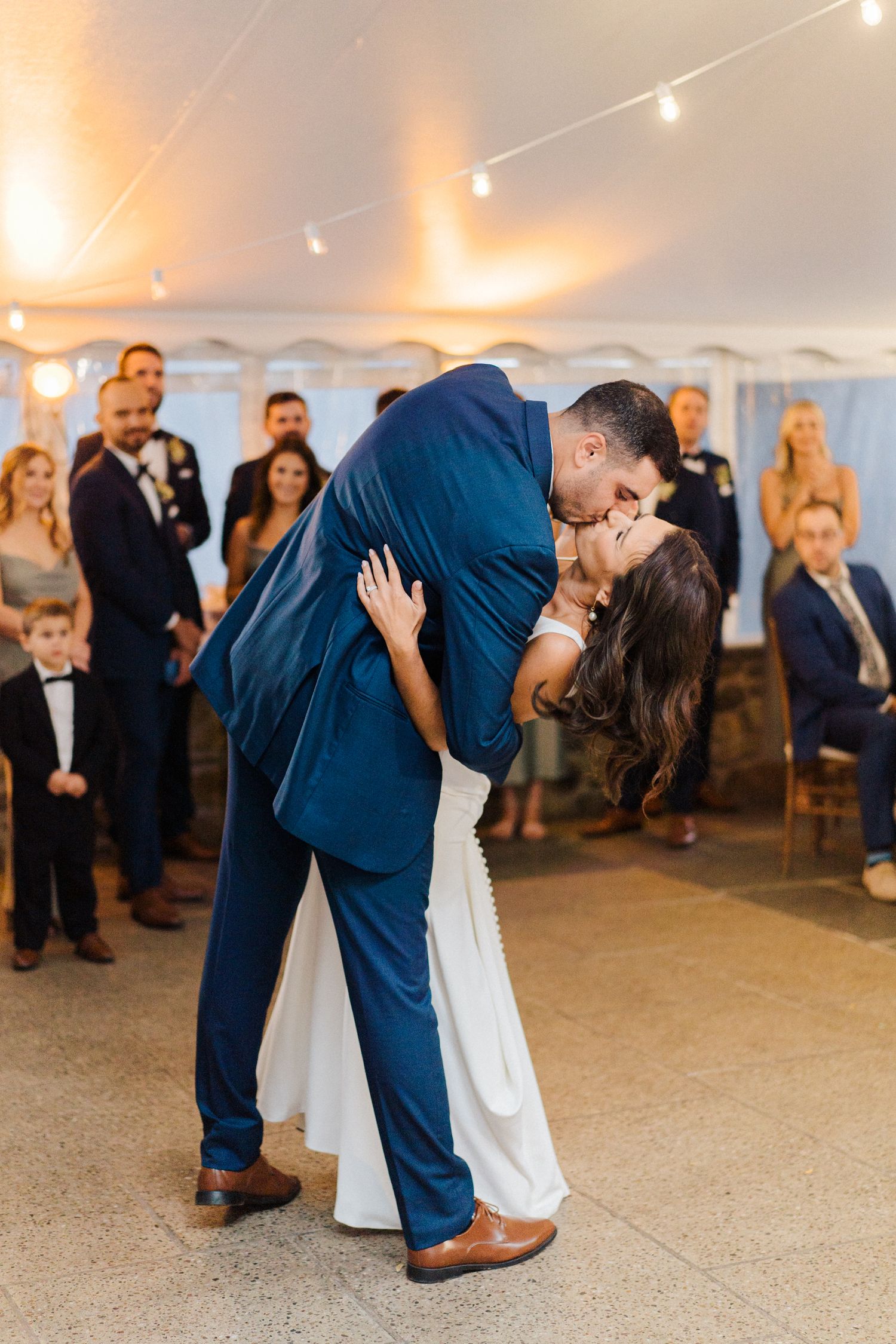 Elegant first dance with dramatic dip under tent lighting.
