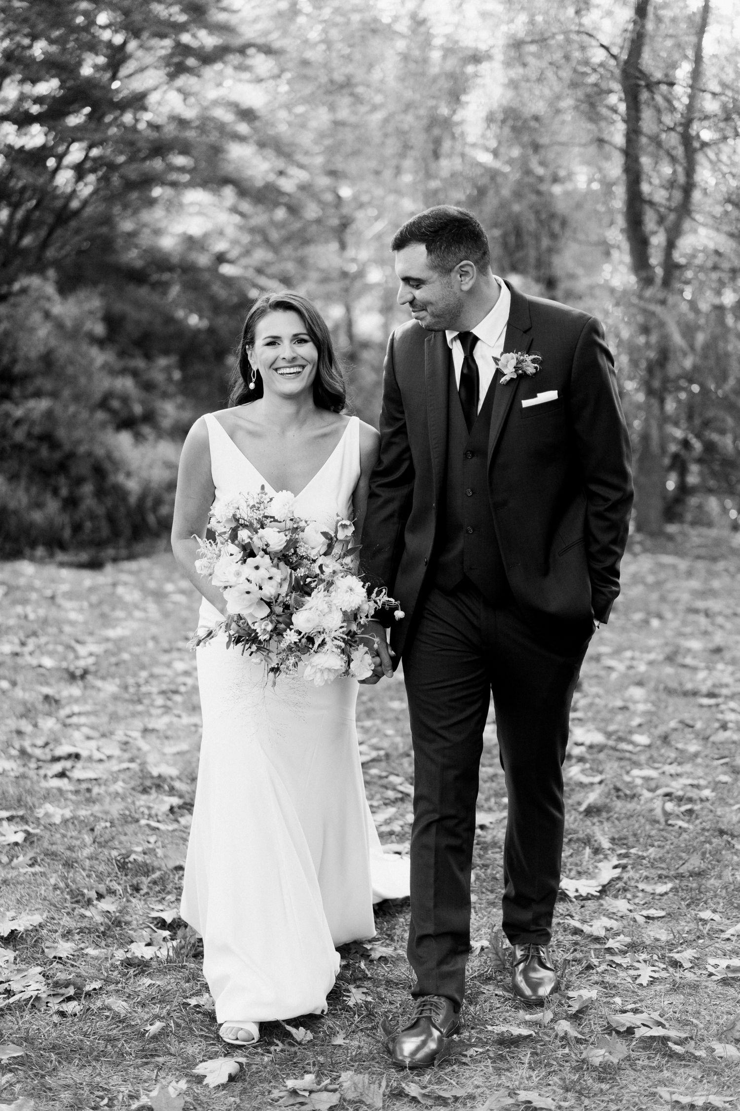 Black and white portrait of newlyweds walking together outdoors.