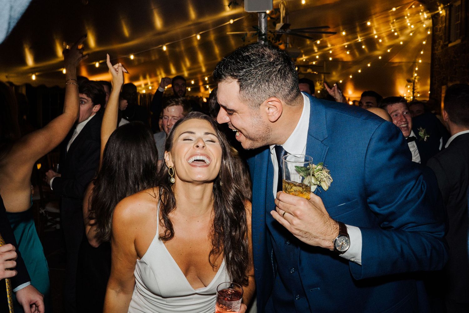 Candid celebration moment under warm reception lighting during wedding festivities.