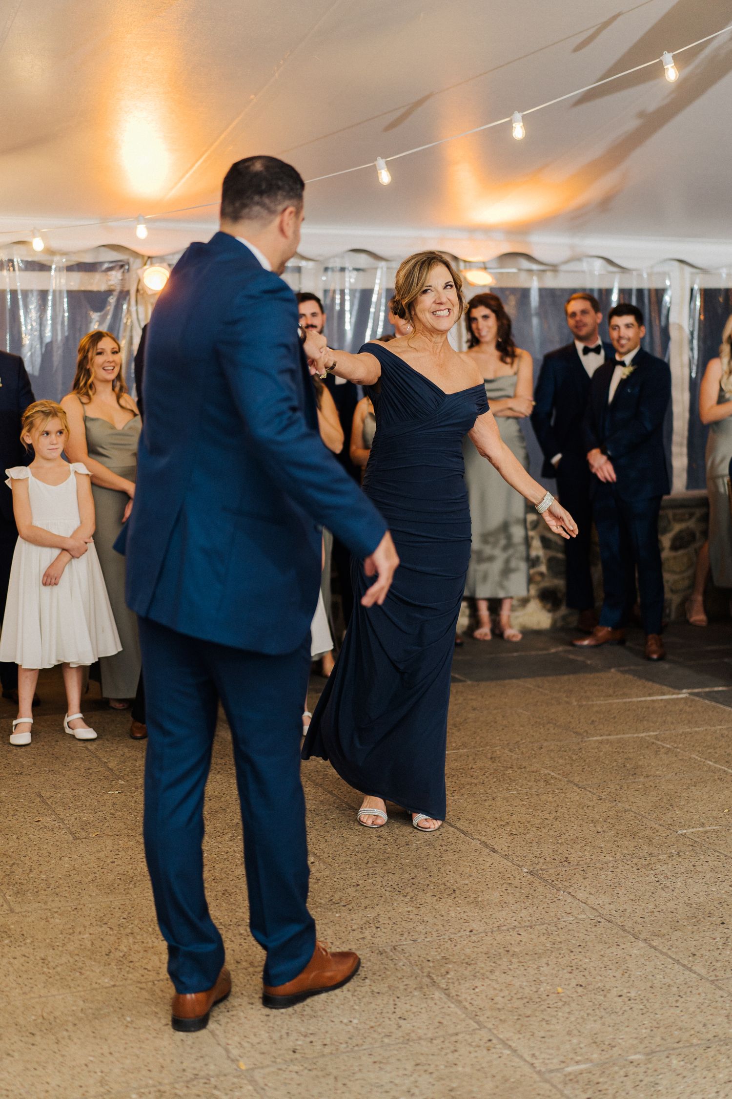 A couple performs a dance move during their wedding reception while guests look on.