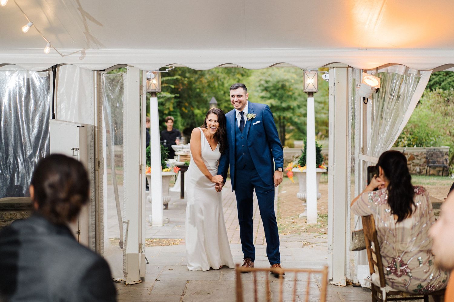Wedding ceremony setup with white drapes and lanterns in garden setting.