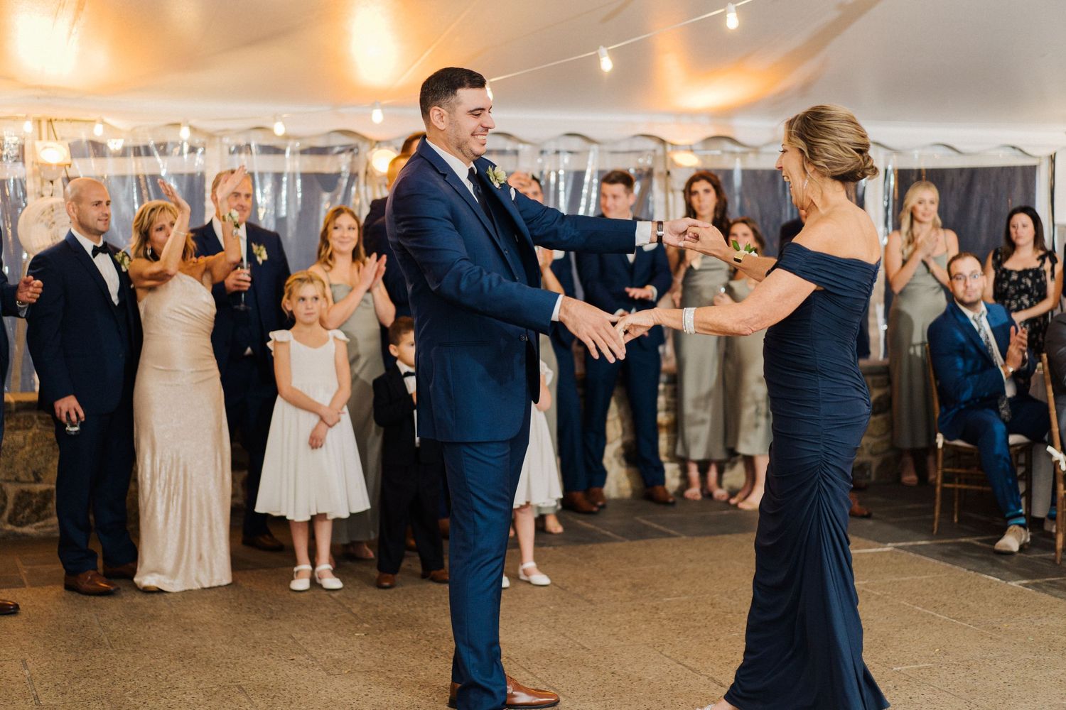 A dancing couple spins on the dance floor while wedding guests cheer and applaud.