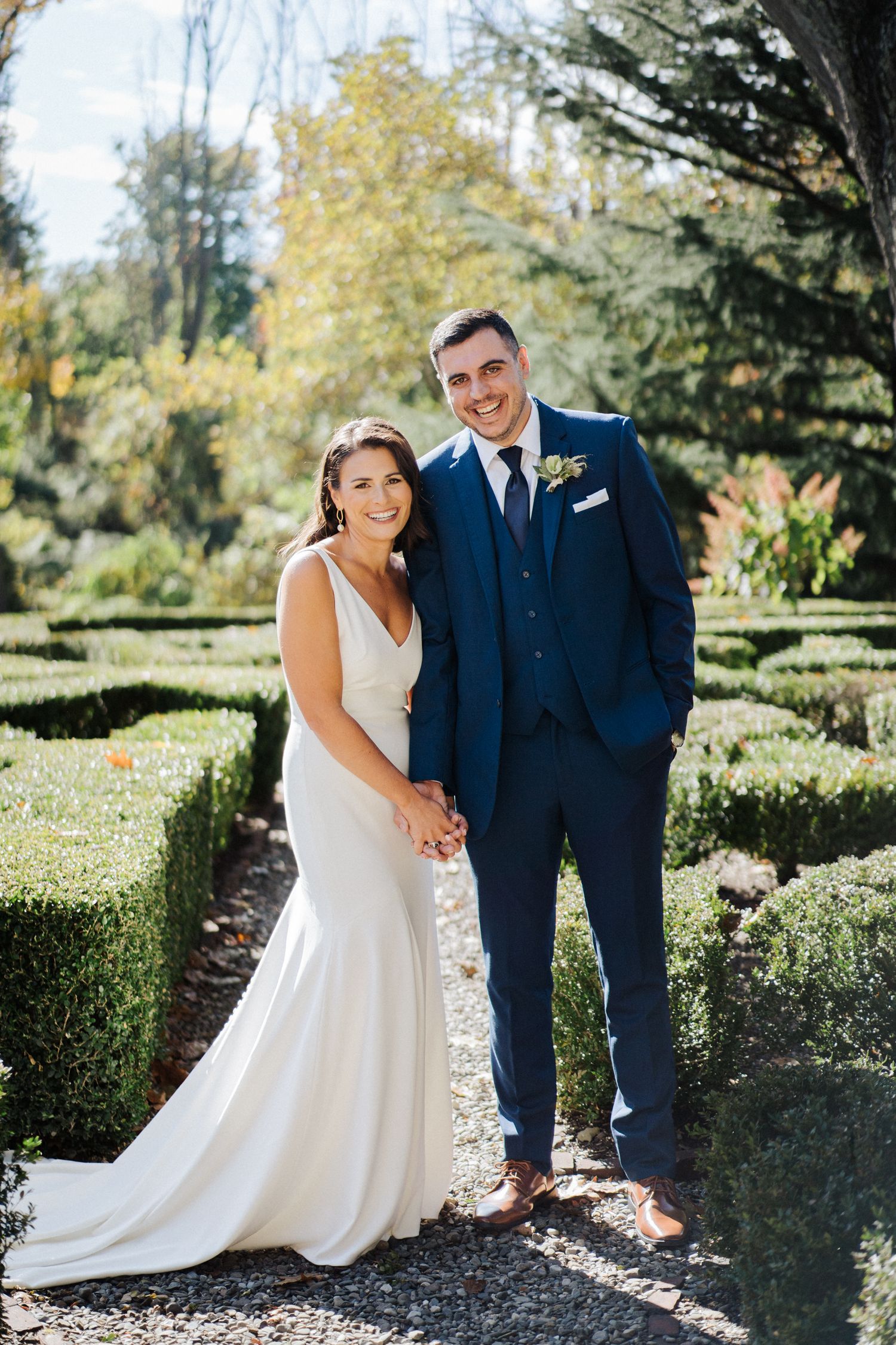 A classic wedding portrait on a garden path with elegant landscaping and autumn colors.