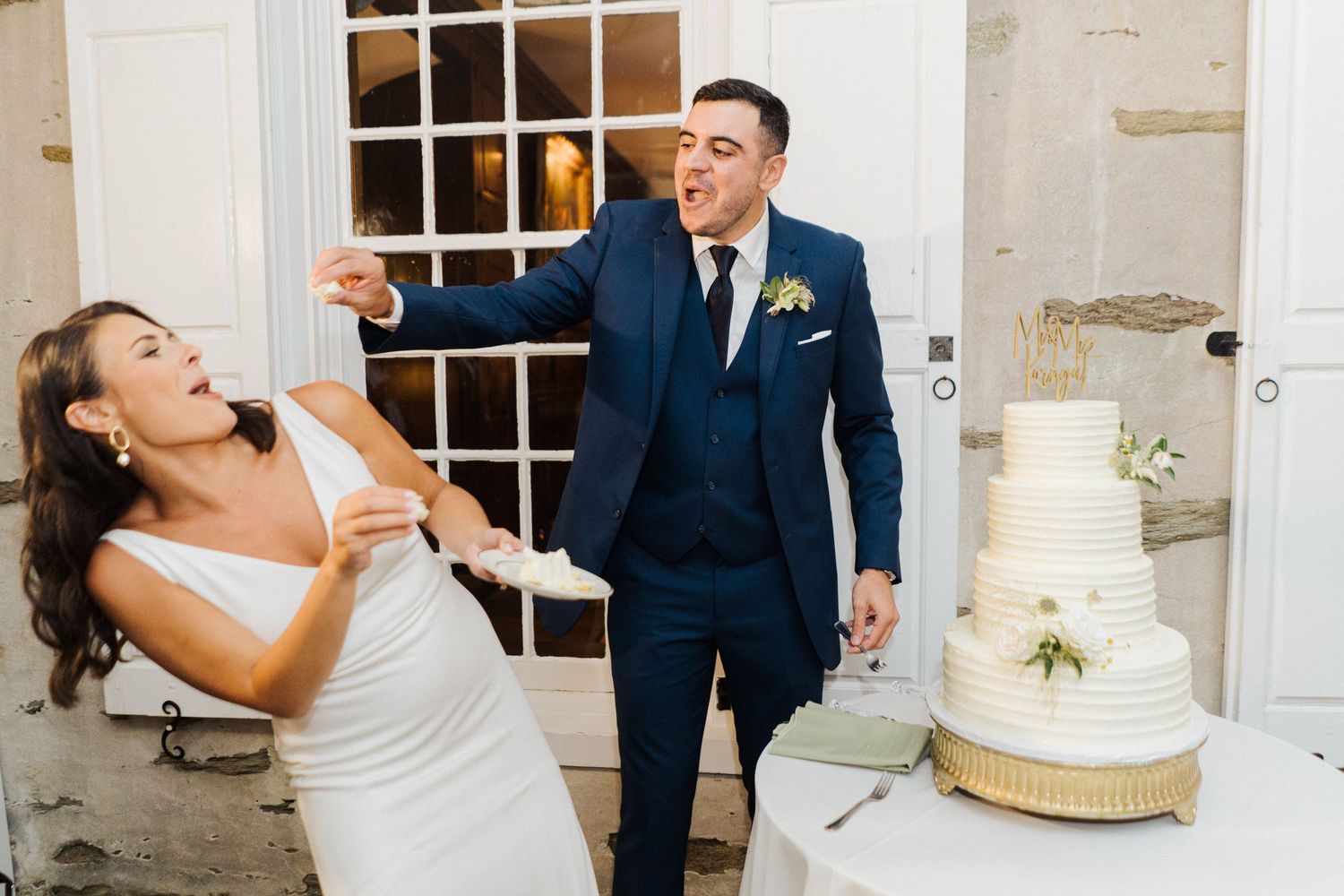 A fun and candid moment during wedding cake tasting at an elegant reception.