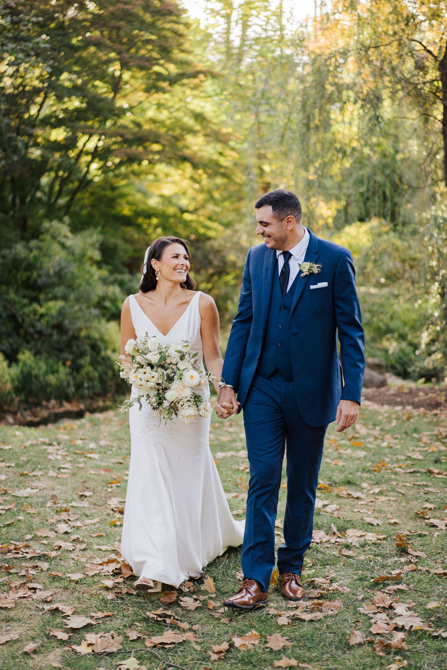Happy couple shares a candid moment while walking on fallen leaves.