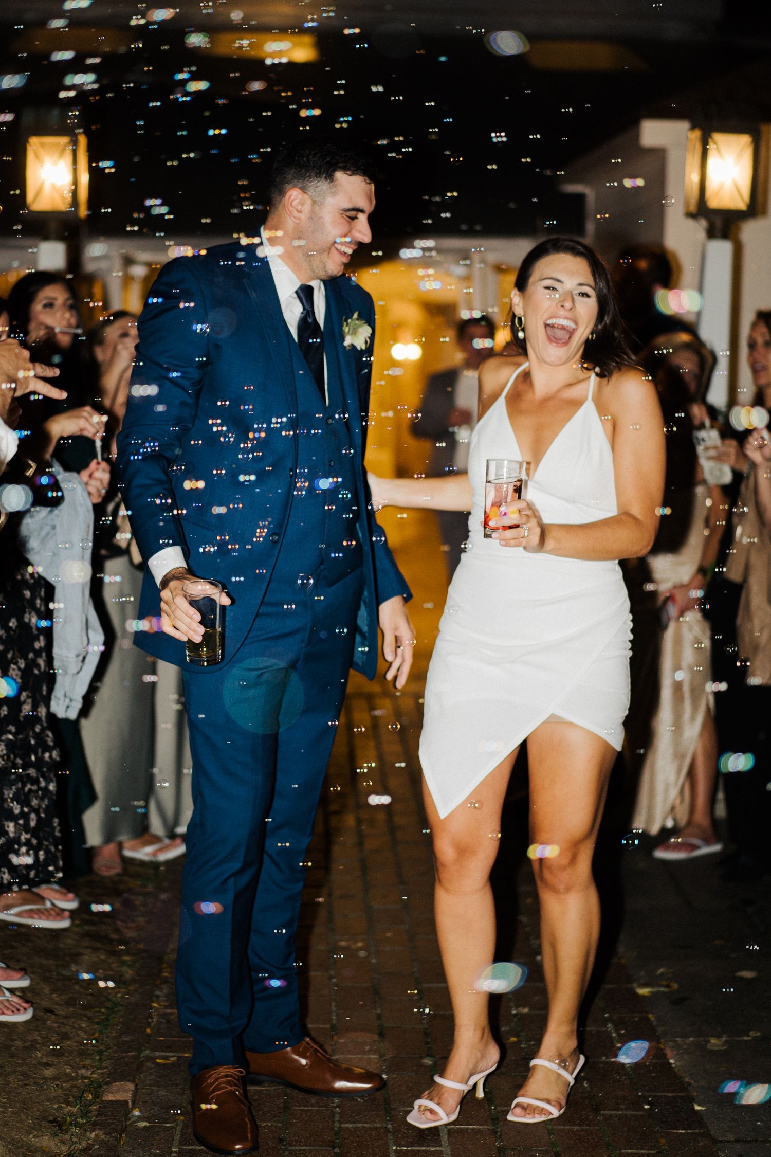 Joyful couple dancing amid bubbles during evening wedding reception.