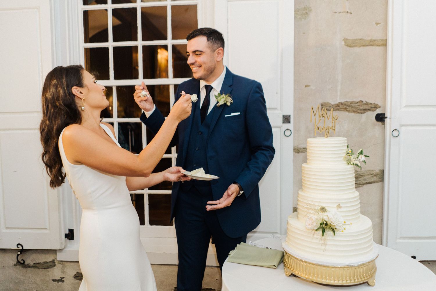 A playful cake cutting moment at a wedding with a tiered white cake.