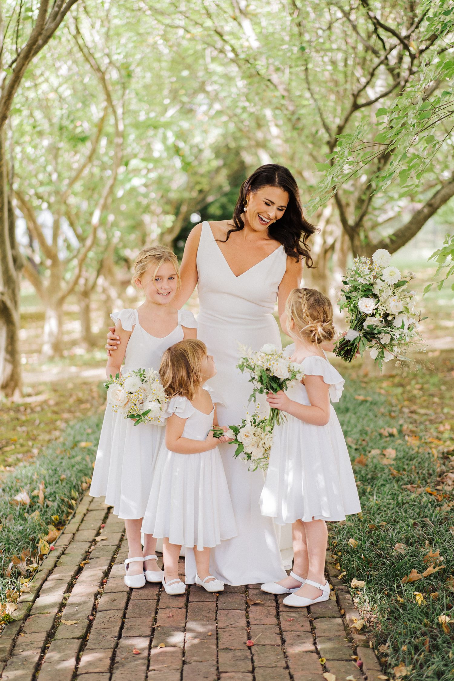 Sweet outdoor portrait on brick pathway with matching white dresses and bouquets.