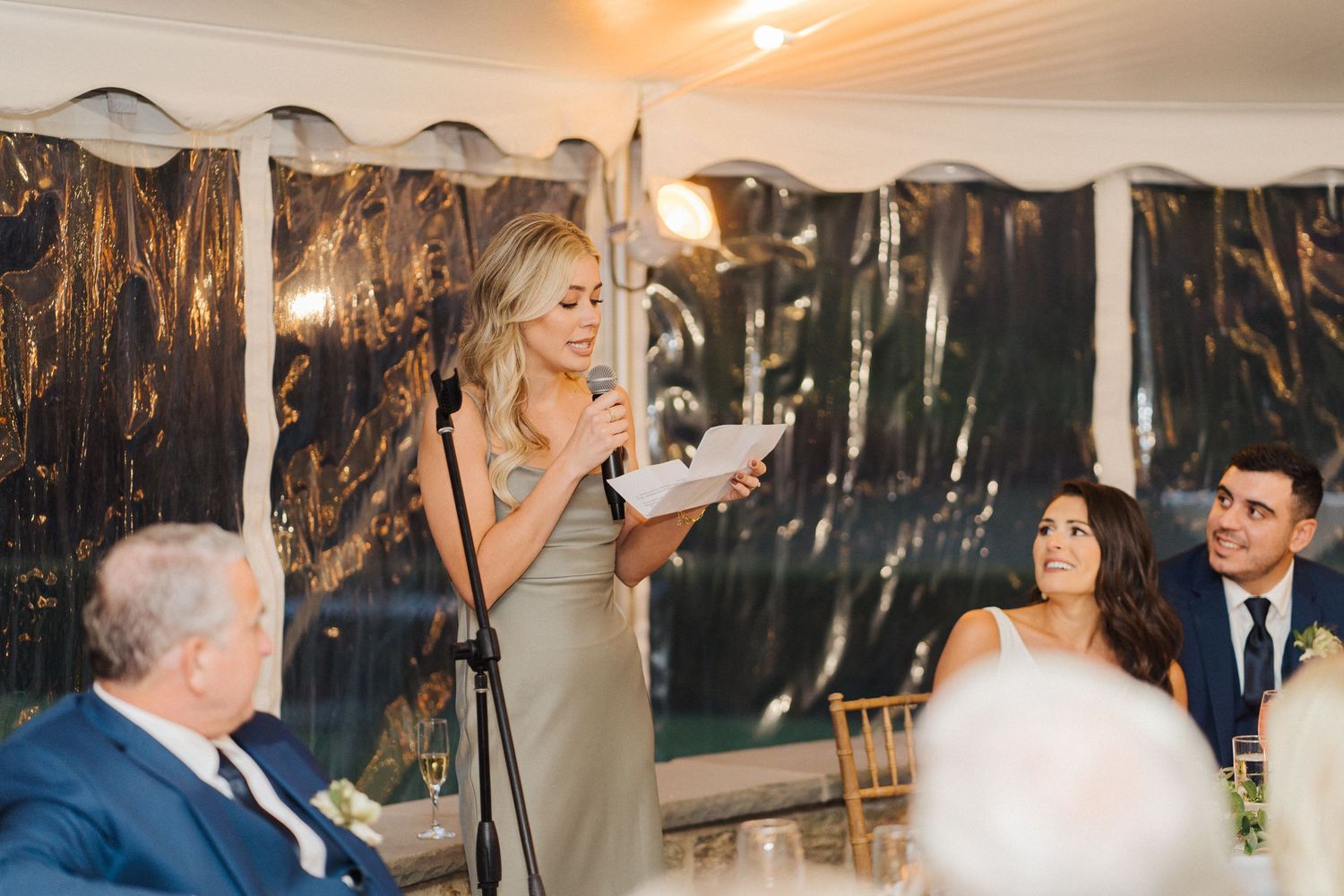 A woman in a grey dress delivers a heartfelt toast at the wedding reception.