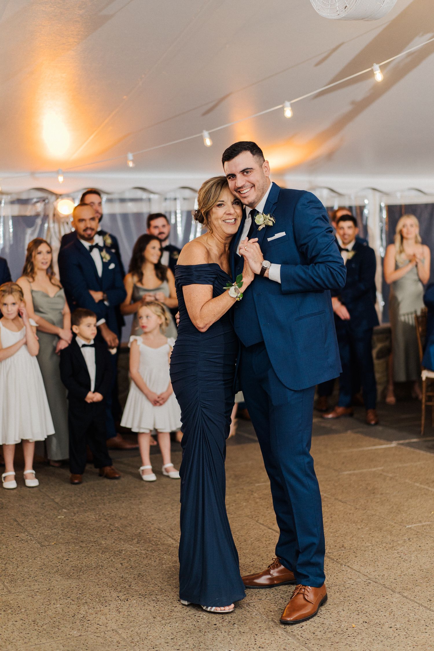 A couple shares a joyful moment during their dance at an elegant tented wedding reception.