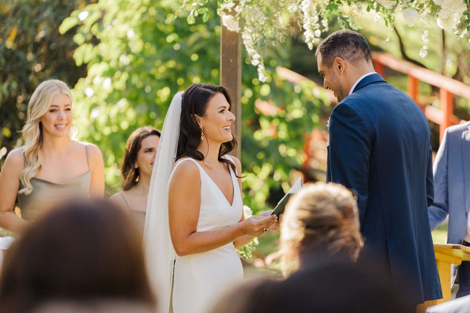 A couple exchanges vows during a sunlit outdoor wedding ceremony.