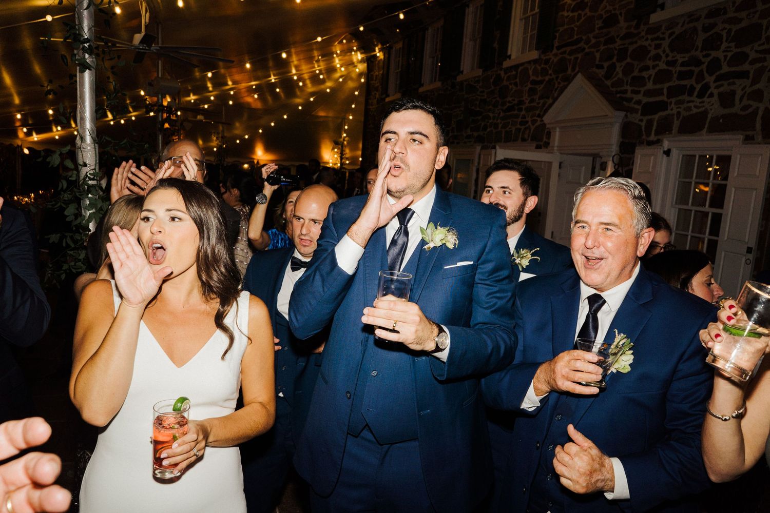 Wedding guests celebrate with drinks during an evening reception.