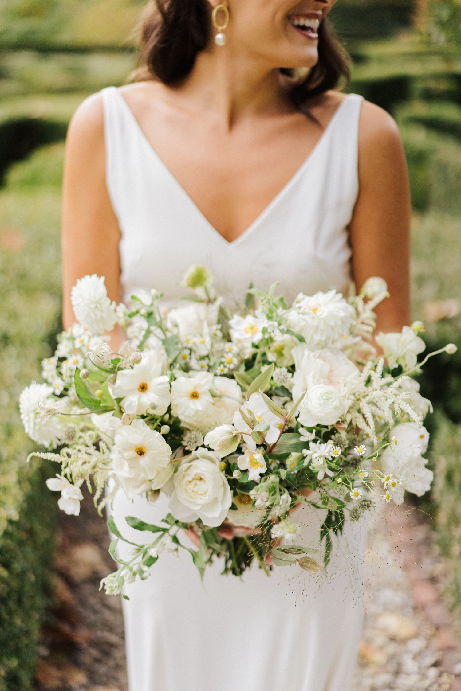 Beautiful white wedding bouquet with roses and mixed flowers against white dress.