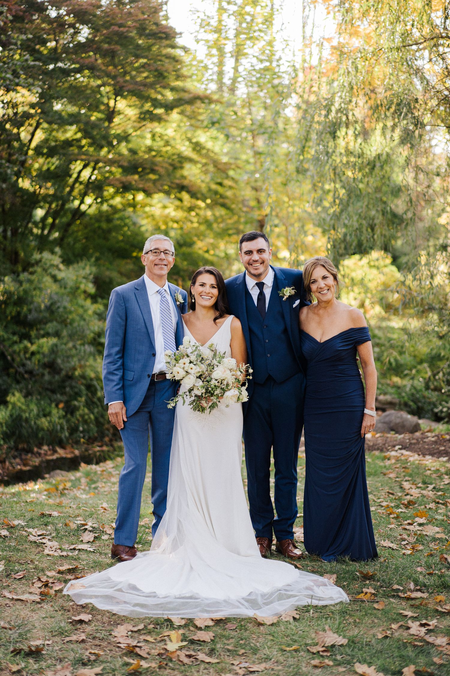 Wedding group photo with bride in white gown and guests in blue formal attire.