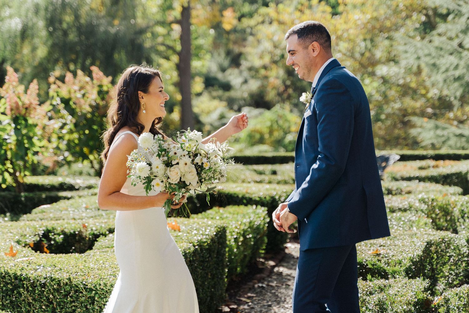 Couple sharing first look moment in manicured garden setting.