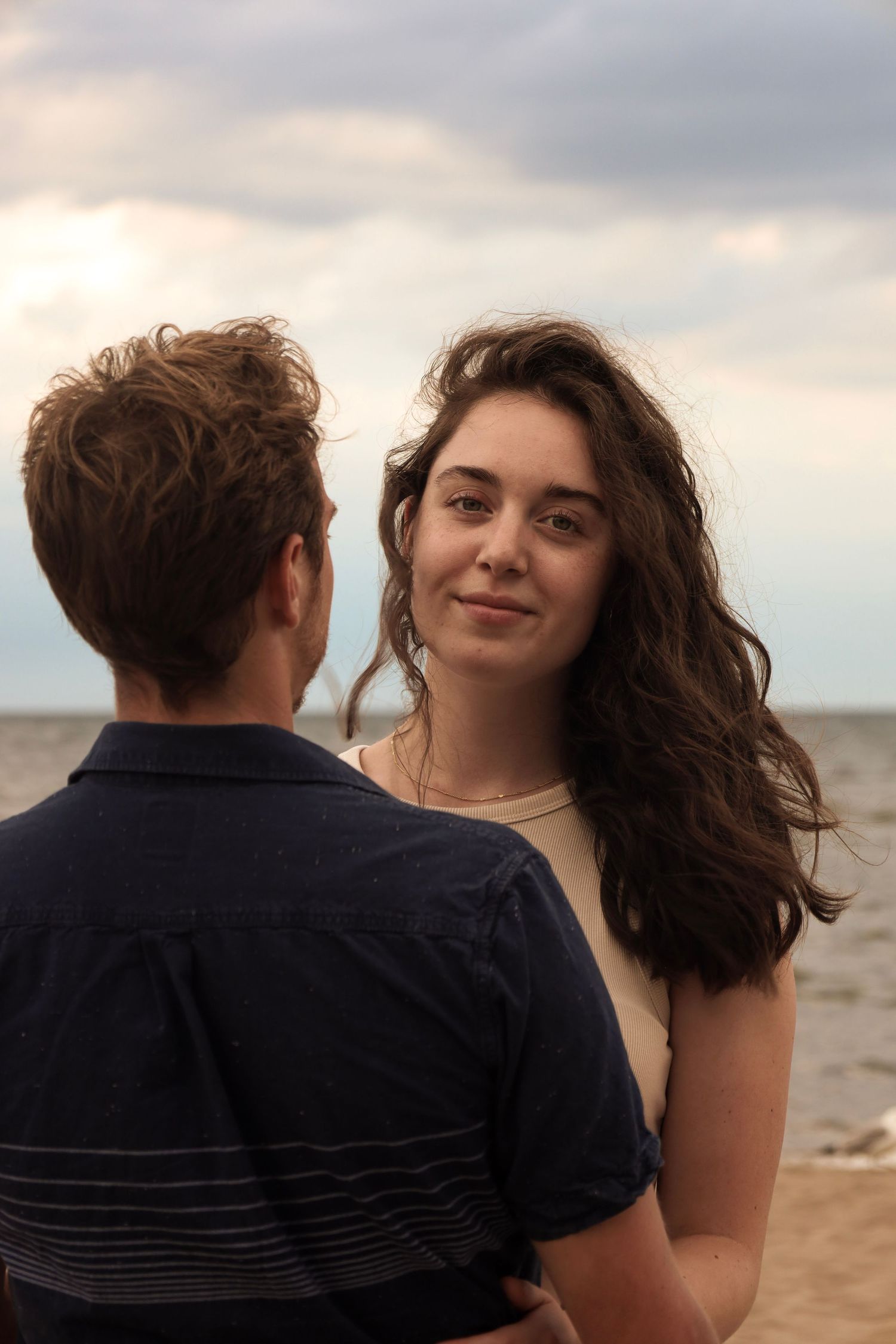 A sequence of romantic photos showing a couple on a beach at sunset with dramatic cloudy skies.