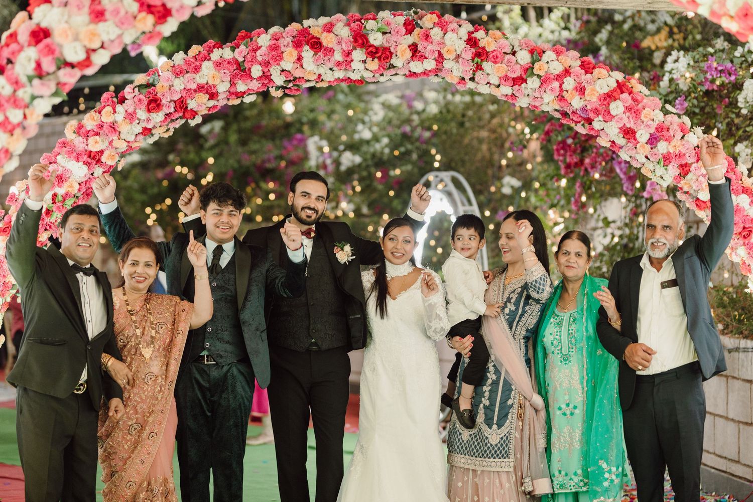 Wedding celebration under pink floral decorations with guests in formal attire.