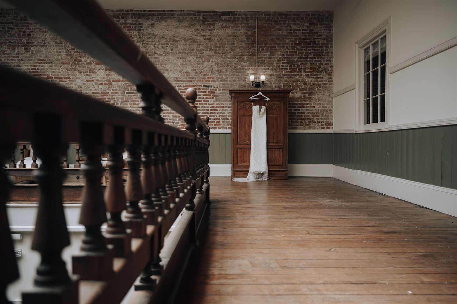 An empty hallway with dark wooden railings and exposed brick walls in a historic venue.